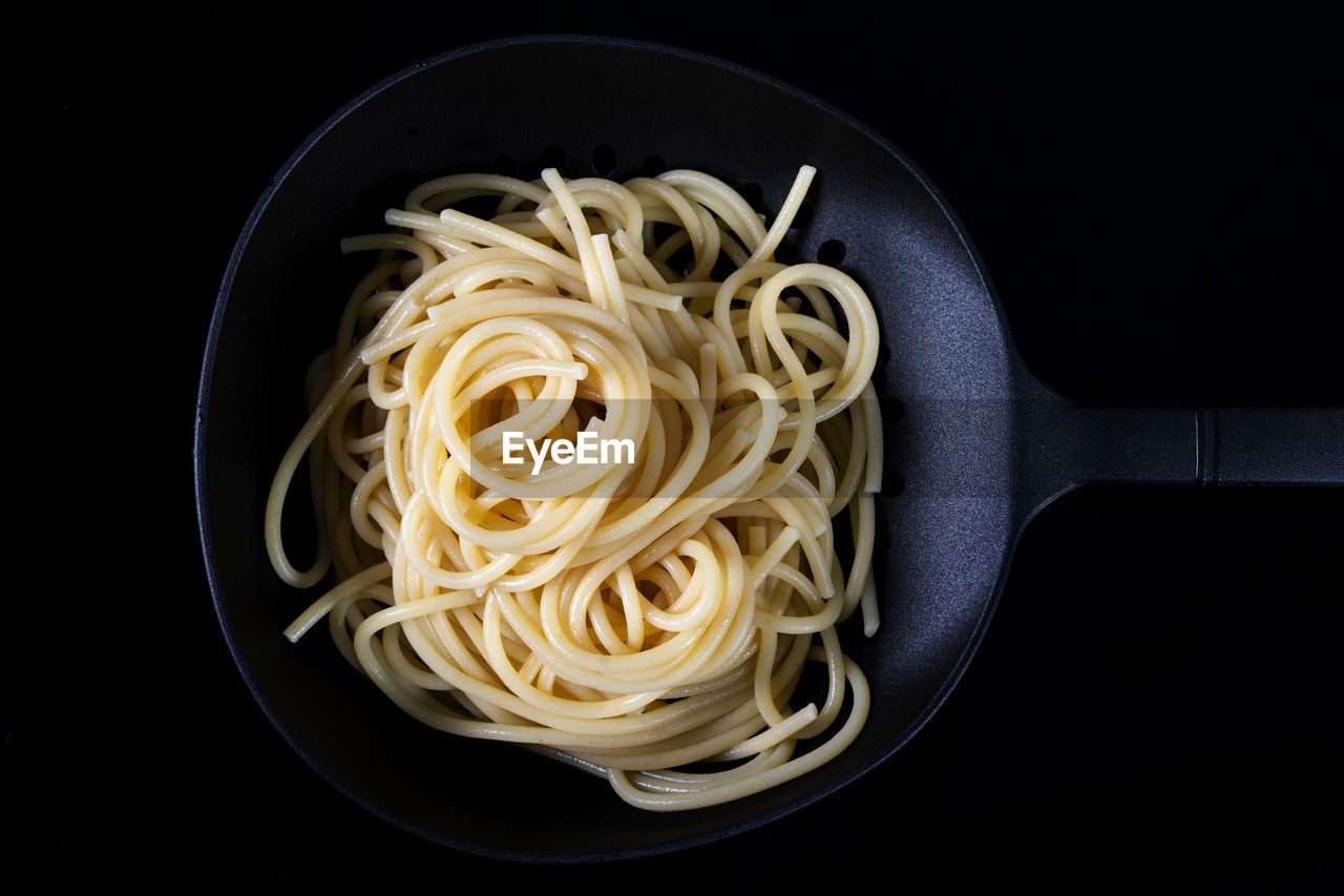 pasta, italian food, food, food and drink, black background, spaghetti, indoors, kitchen utensil, freshness, studio shot, healthy eating, carbonara, no people, wellbeing, cuisine, household equipment, close-up, directly above, vegetable, produce, high angle view, cooking pan, eating utensil, meal
