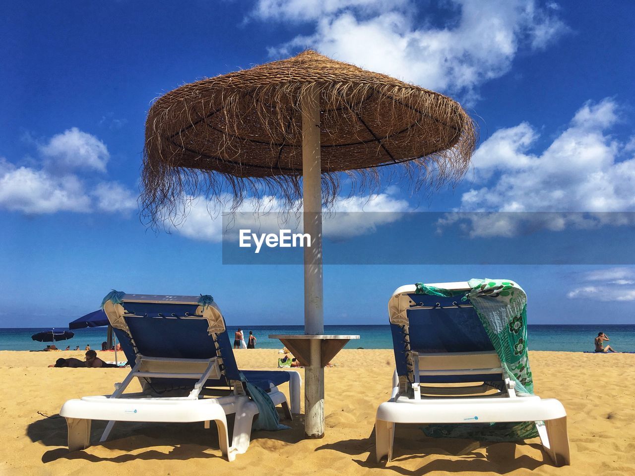 LOUNGE CHAIRS ON BEACH AGAINST SKY
