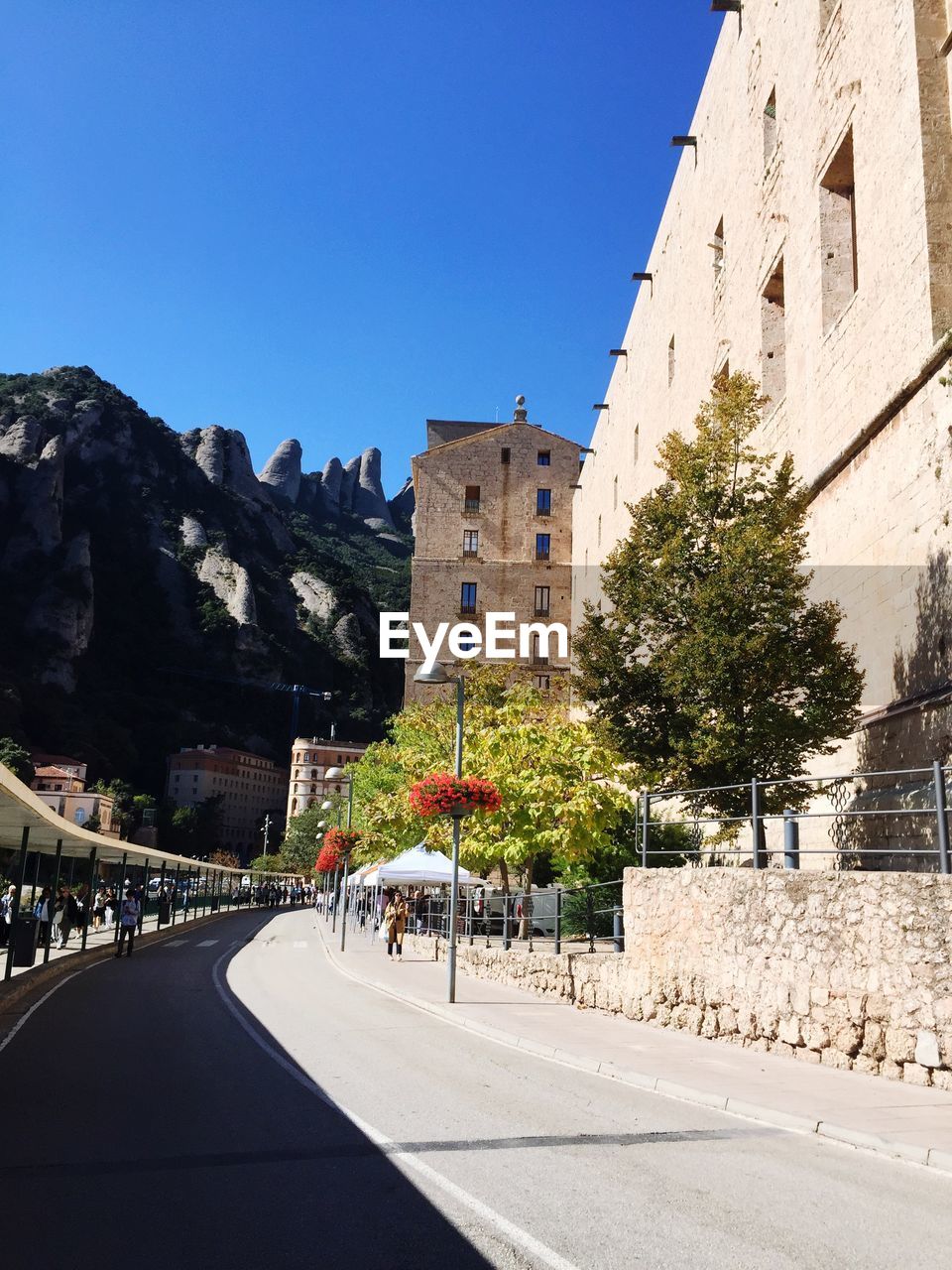 Road by buildings against clear blue sky