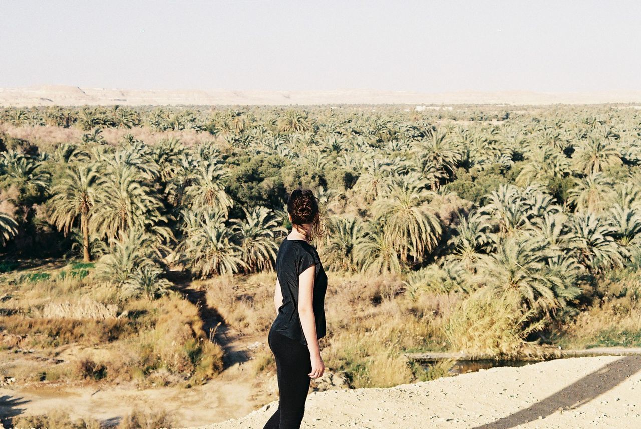 Side view of woman standing on field against sky