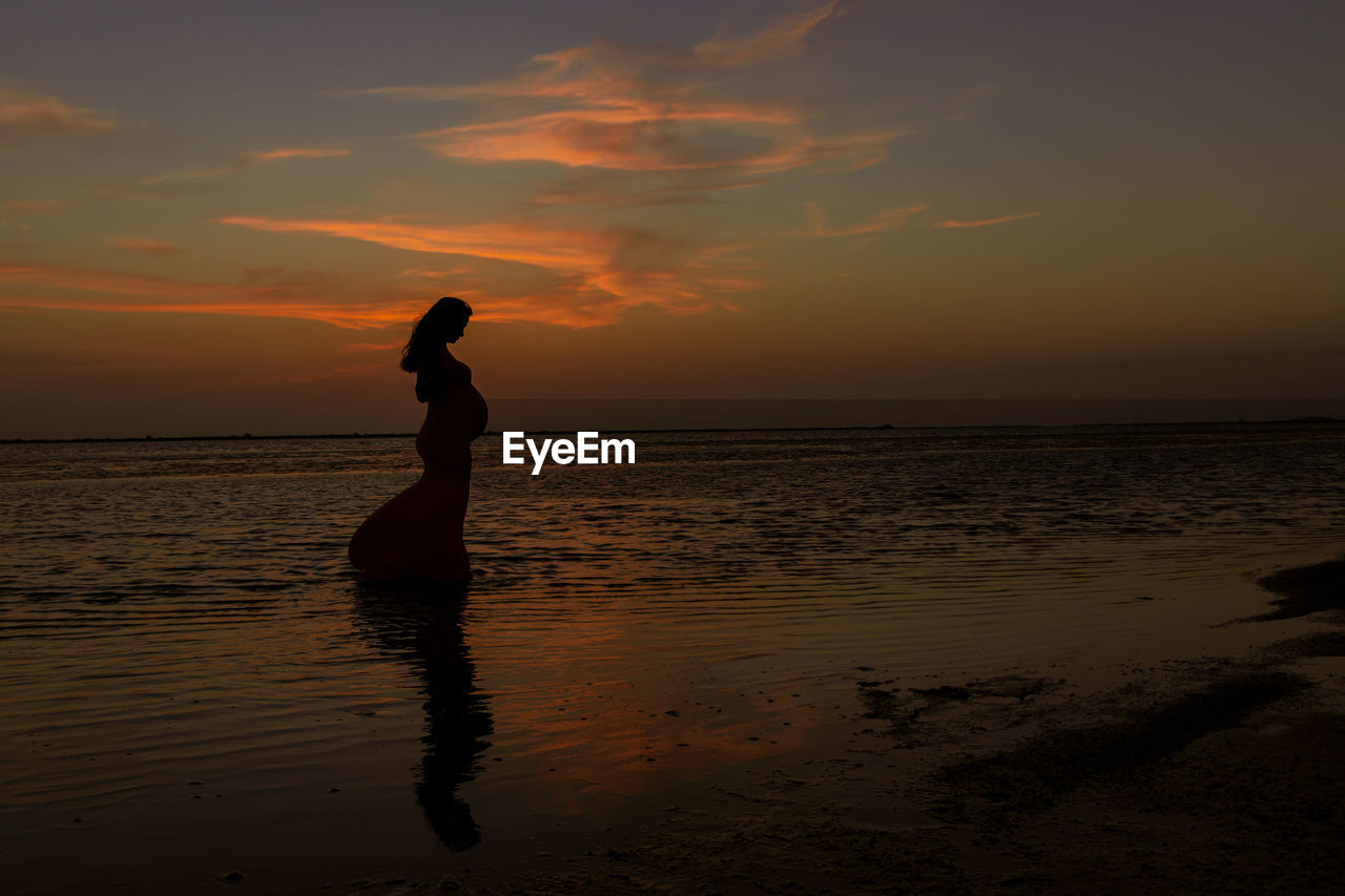 SILHOUETTE WOMAN AT BEACH DURING SUNSET