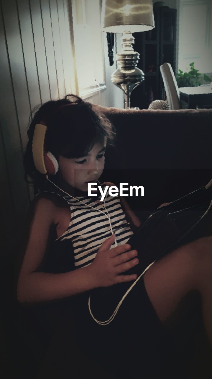 Girl listening to music while using digital tablet at home