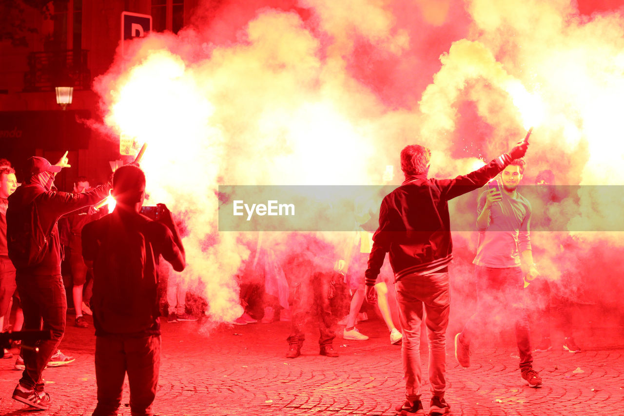 REAR VIEW OF PEOPLE WITH FIRE CRACKERS AT NIGHT