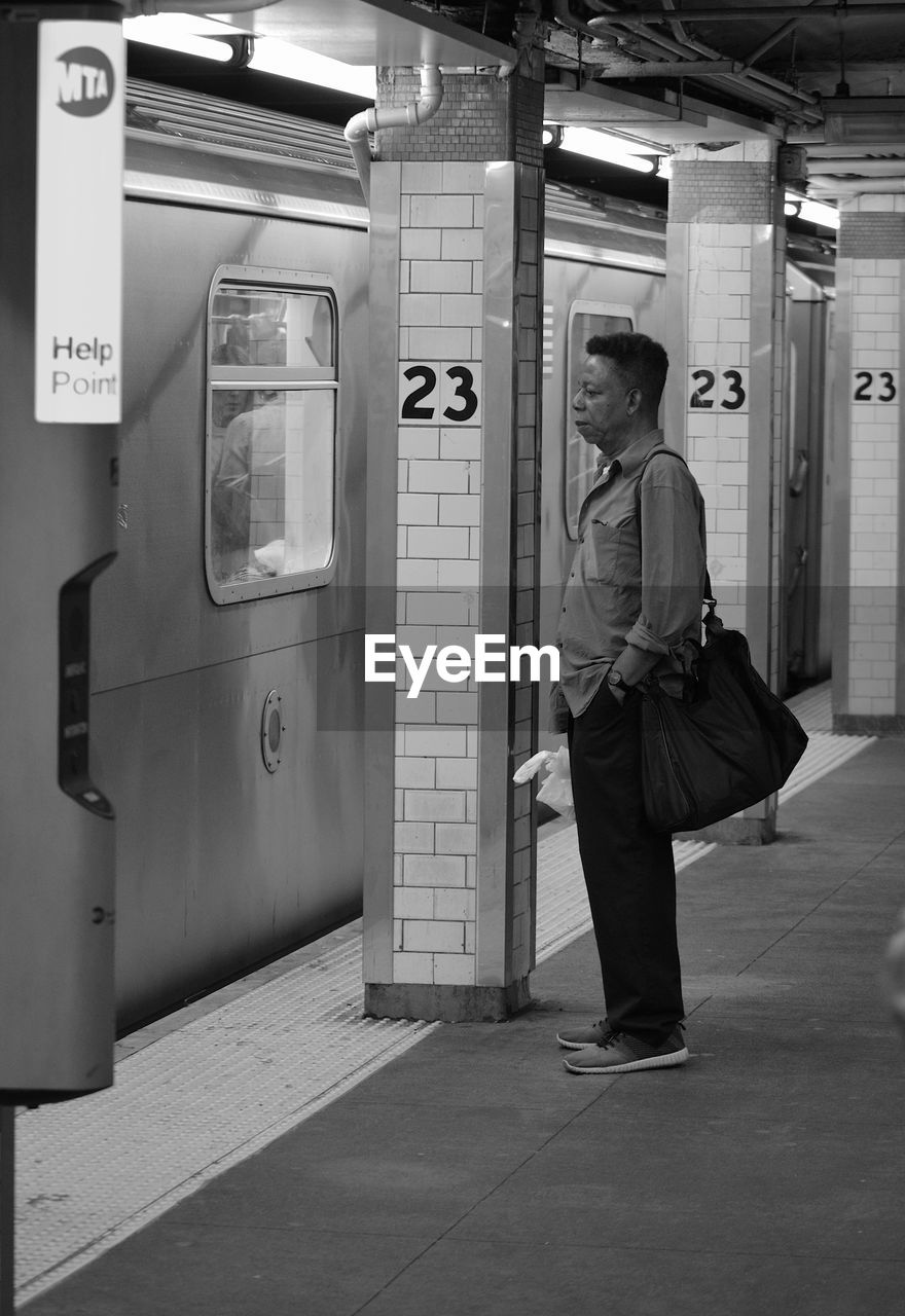 MAN STANDING AT RAILROAD STATION