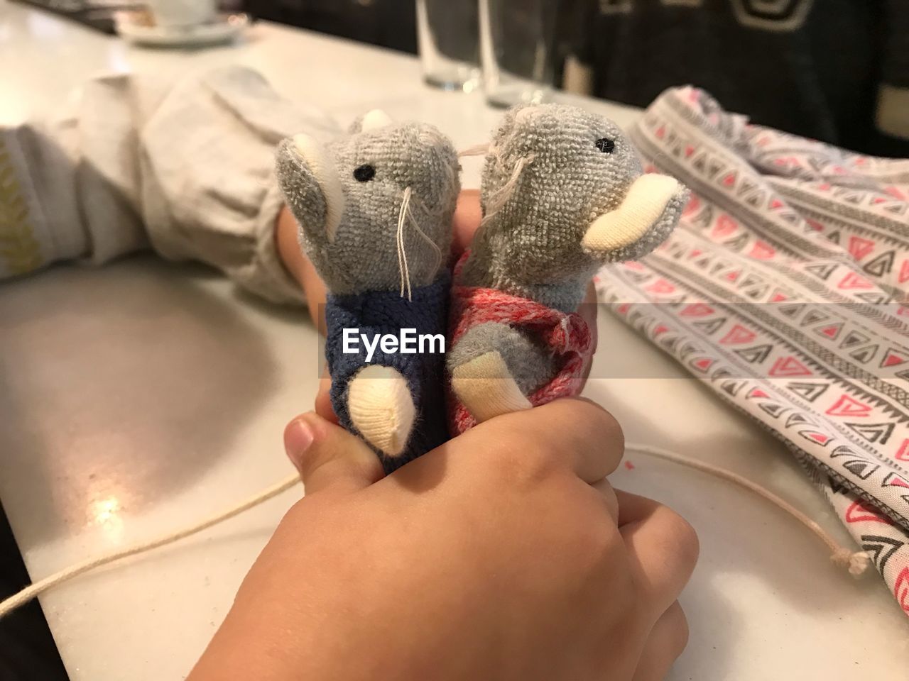 Cropped hands of girl holding toy animals at table