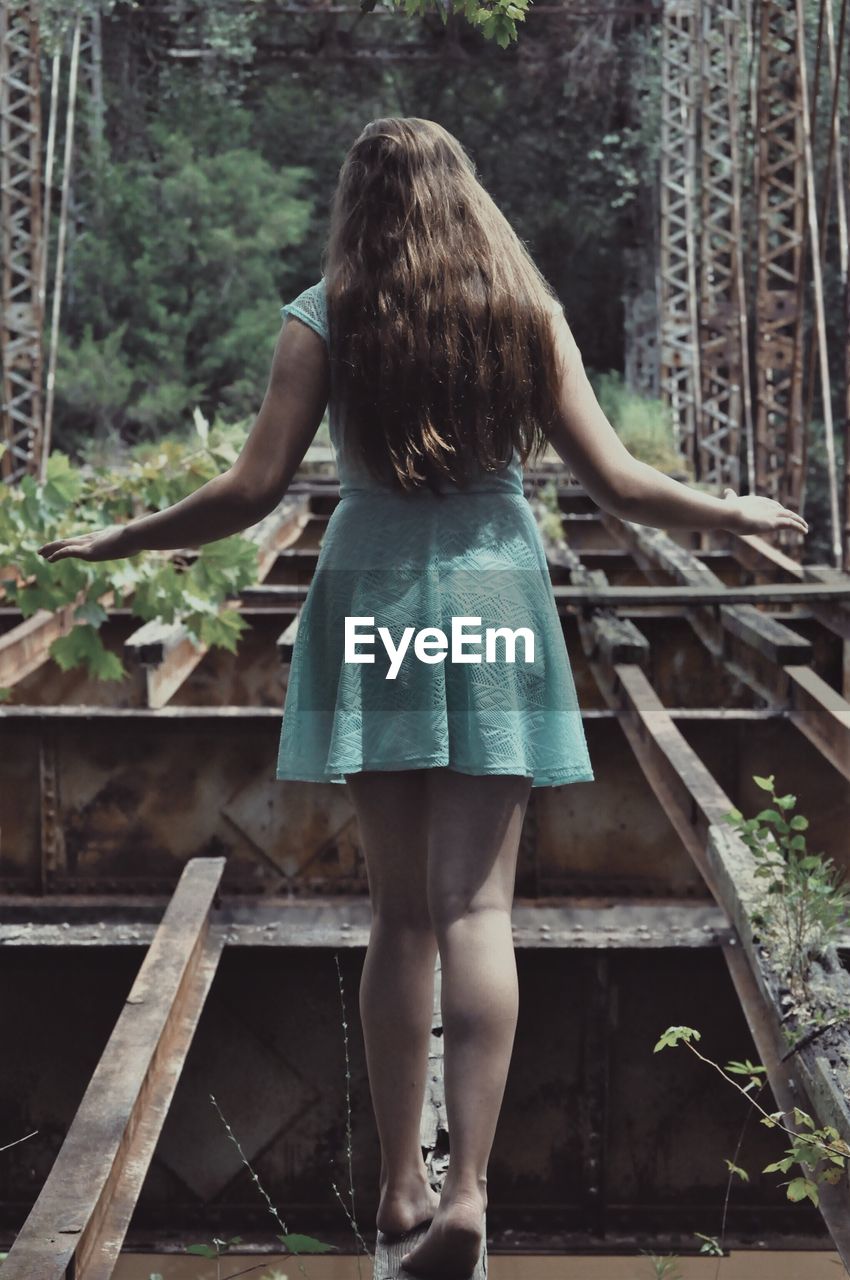 Rear view of woman standing on abandoned bridge