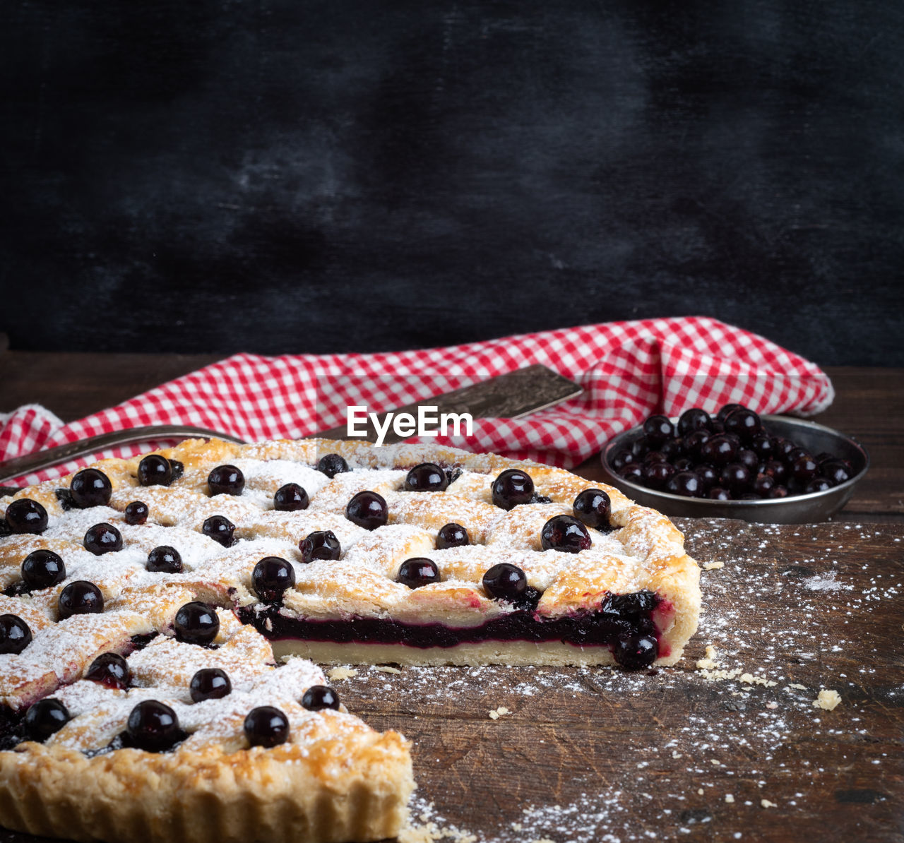 Close-up of tart with black currants on table against black background