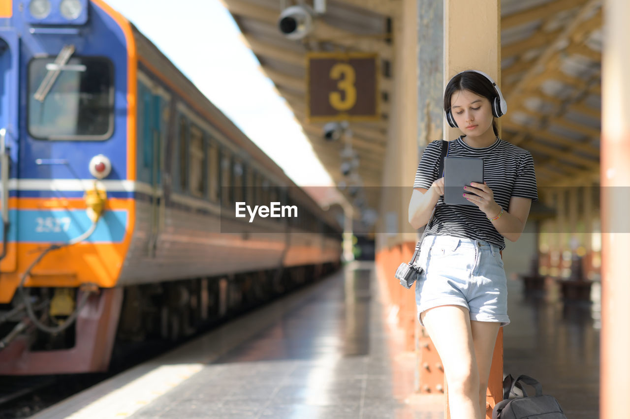 A teenage woman wearing headphones listening to music from an app on a tablet.