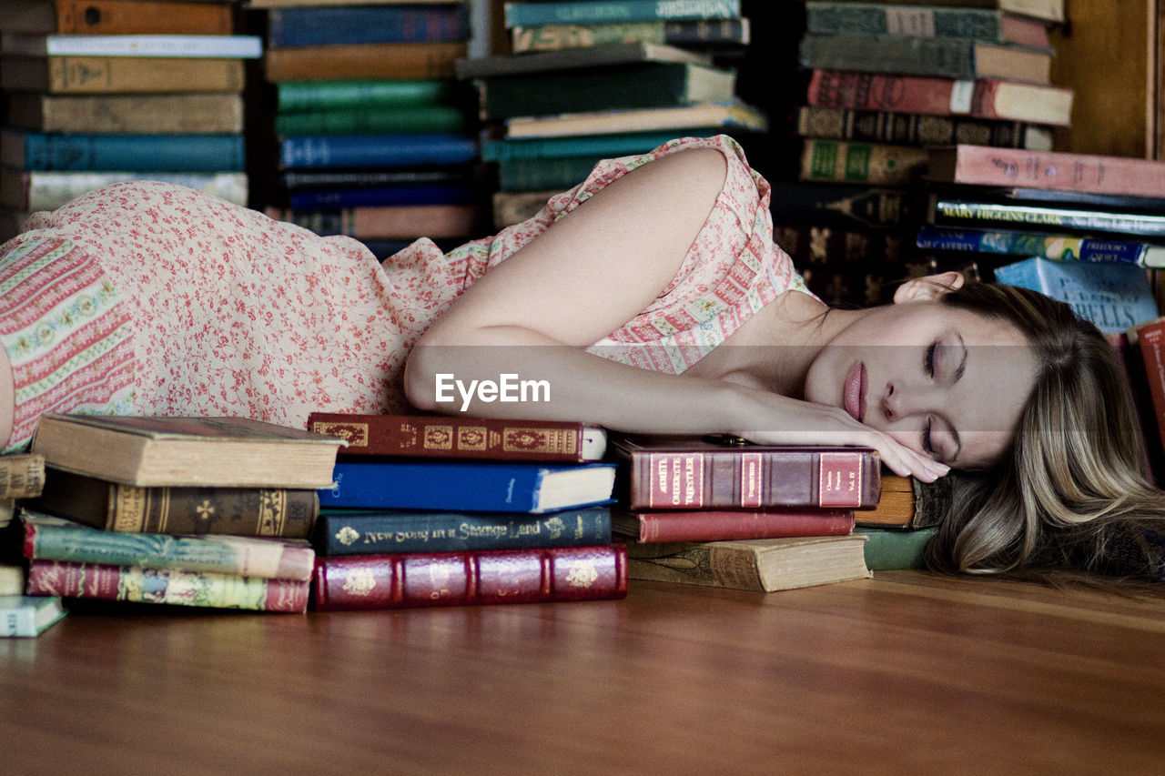 Exhausted young woman sleeping on books