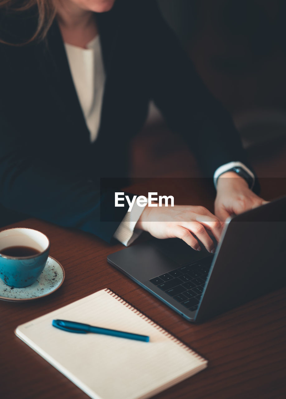 Midsection of woman using laptop on table