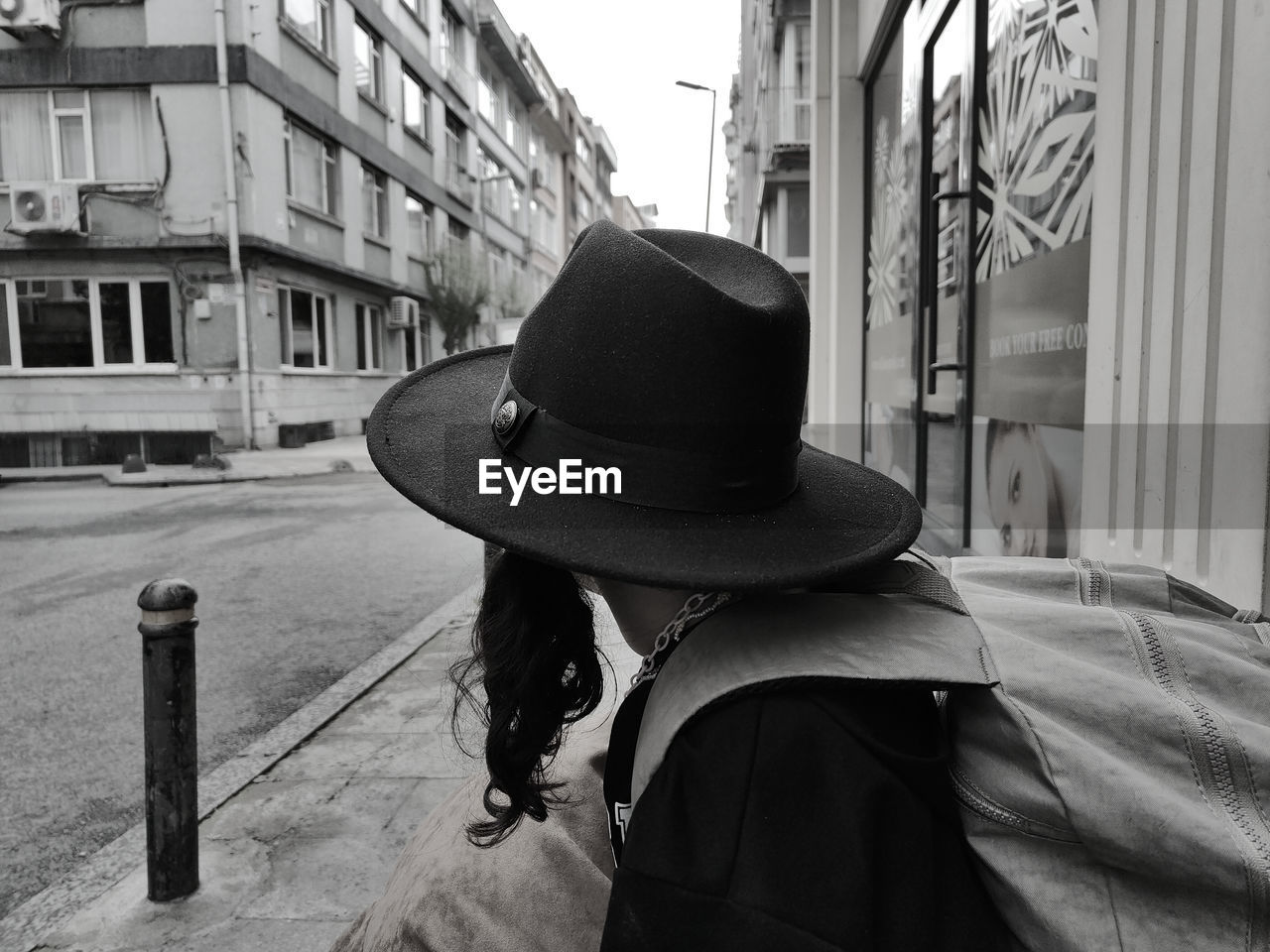 rear view of woman wearing hat while standing in city