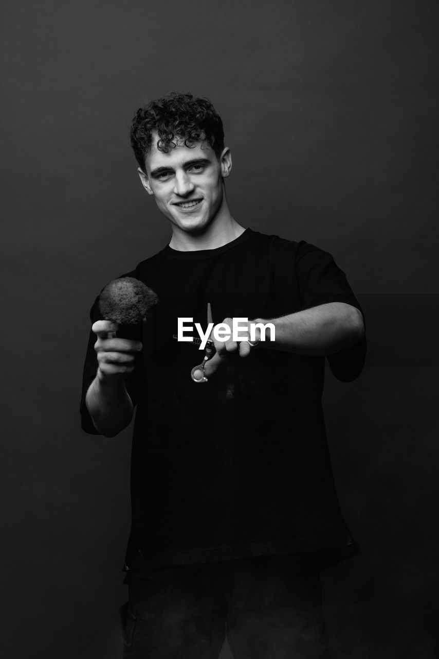 Portrait of young man standing against black background