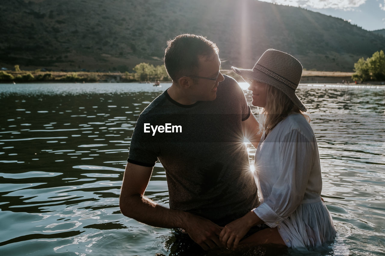 Man and woman standing in a lake smiling and talking on a sunny day