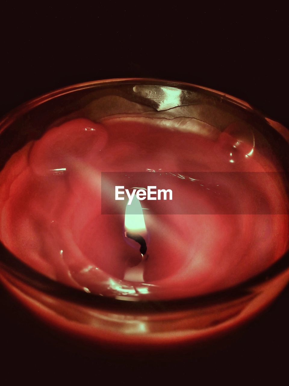 CLOSE-UP OF LIT CANDLE IN BLACK BACKGROUND