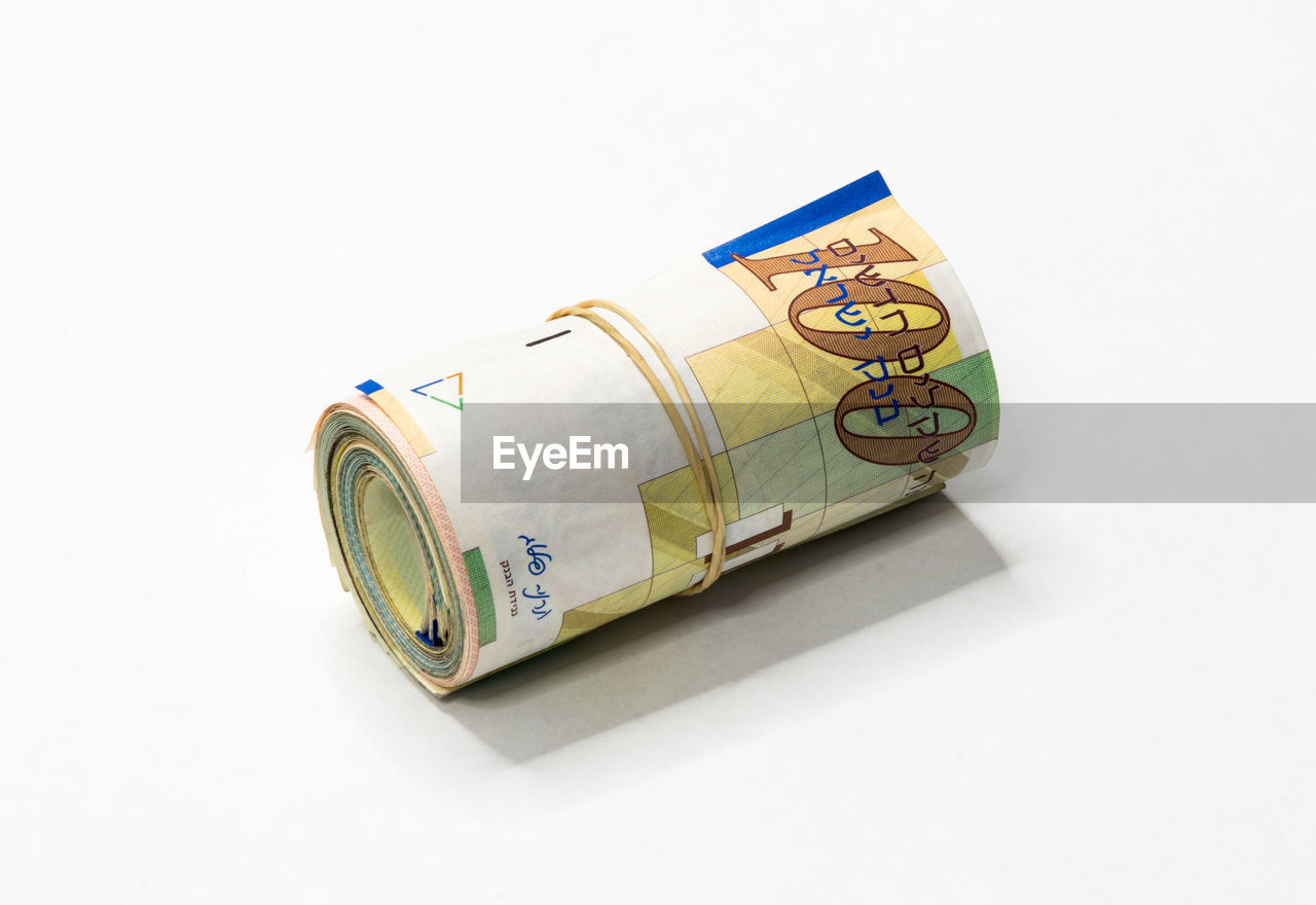 Close-up of rolled up paper currency against white background