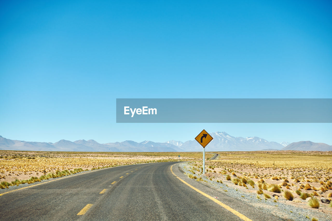 View of road sign against clear blue sky