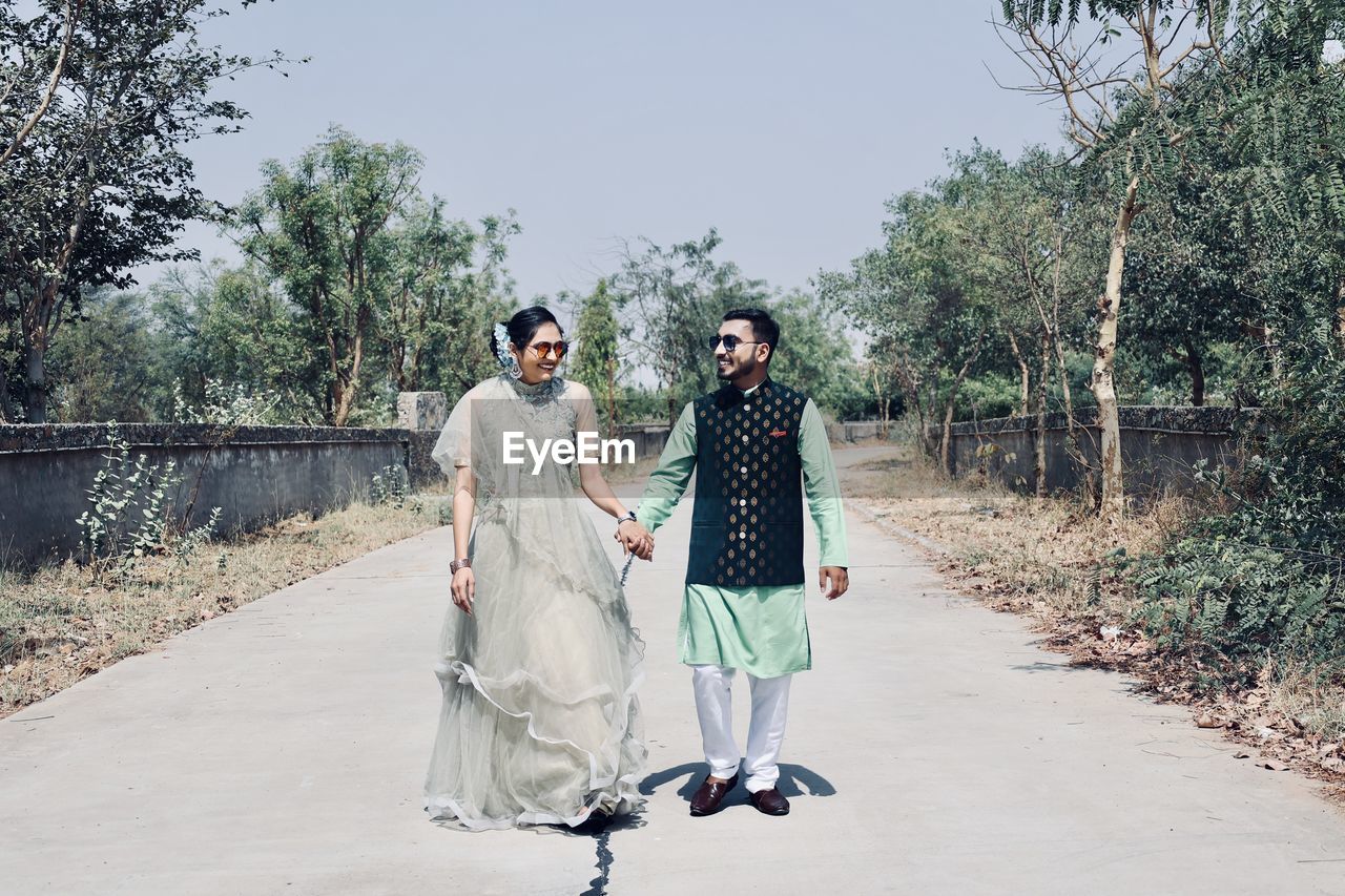 Full length of young couple on road against trees
