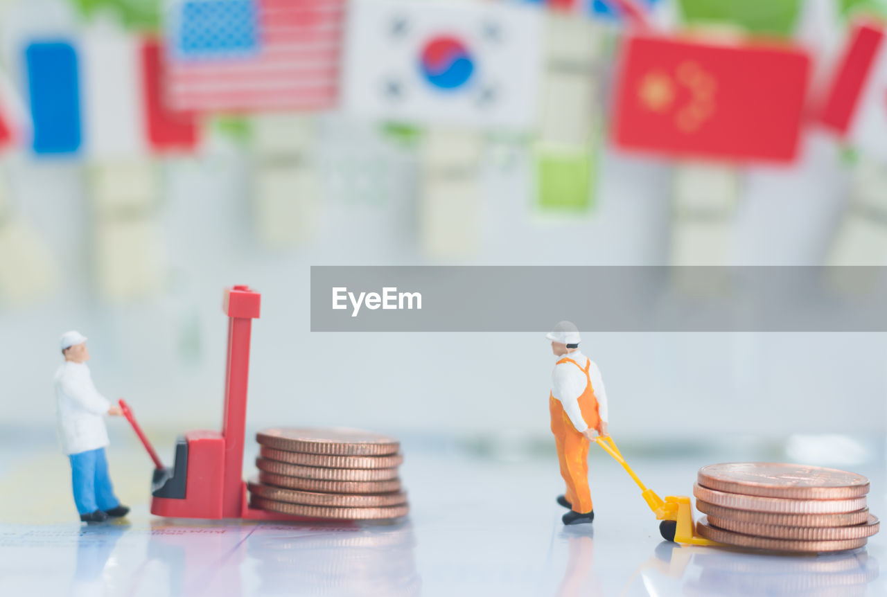 Close-up of figurines pulling coins on table