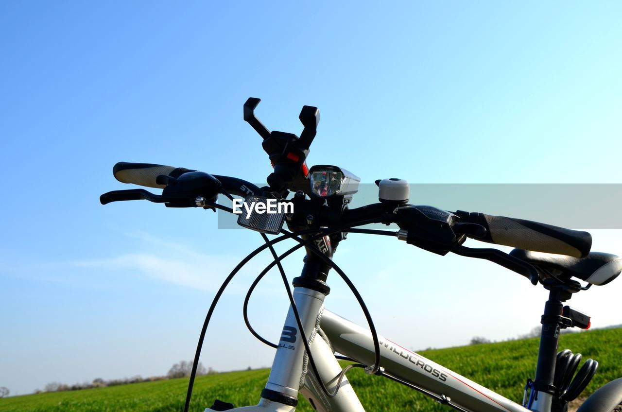 LOW ANGLE VIEW OF BICYCLES ON FIELD AGAINST CLEAR SKY