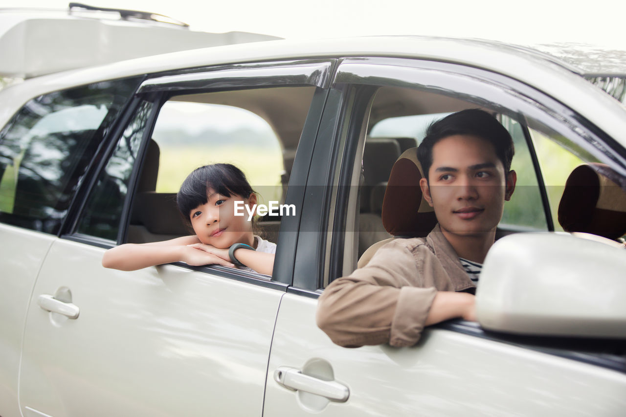 Father and daughter looking through car windows