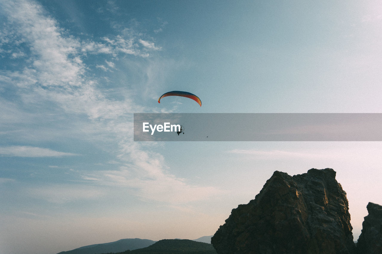 Low angle view of person paragliding against sky