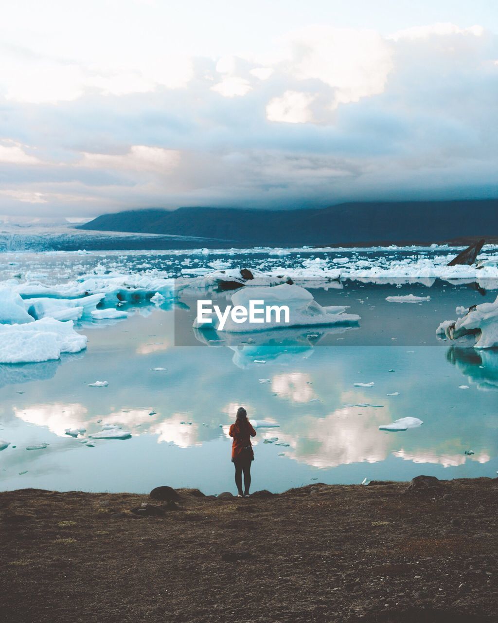 Rear view of woman standing against ice bergs