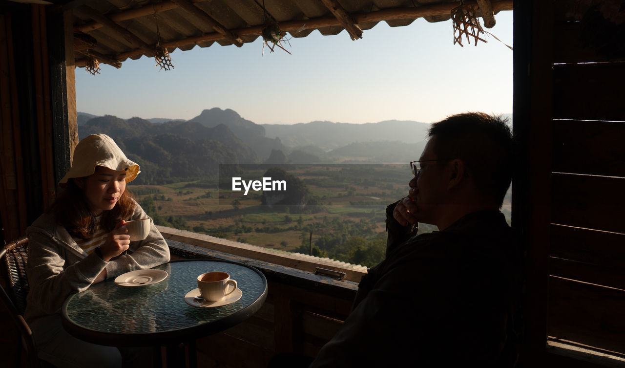 Couple sitting at restaurant against landscape