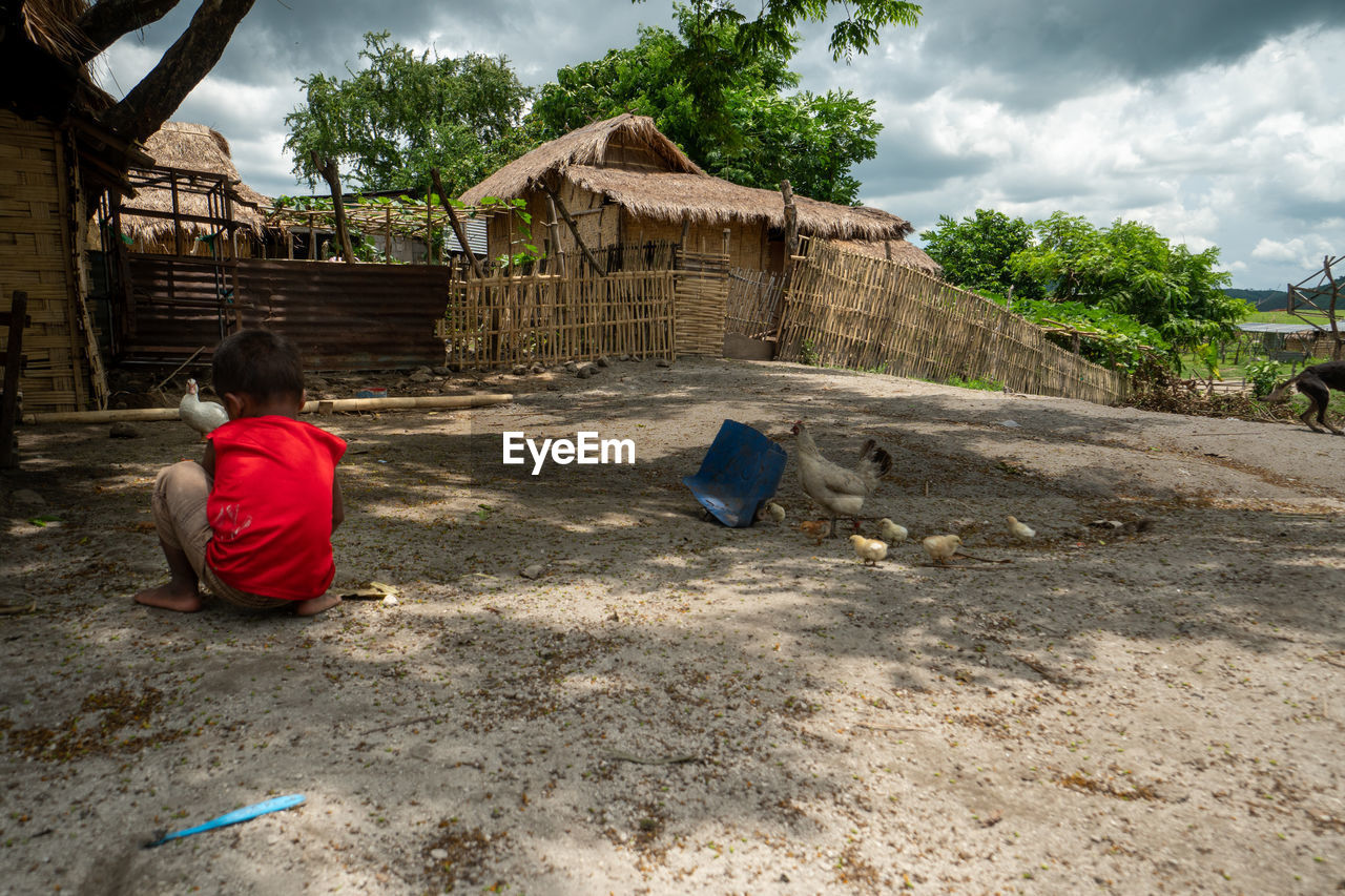 REAR VIEW OF WOMAN SITTING ON STONE STRUCTURE