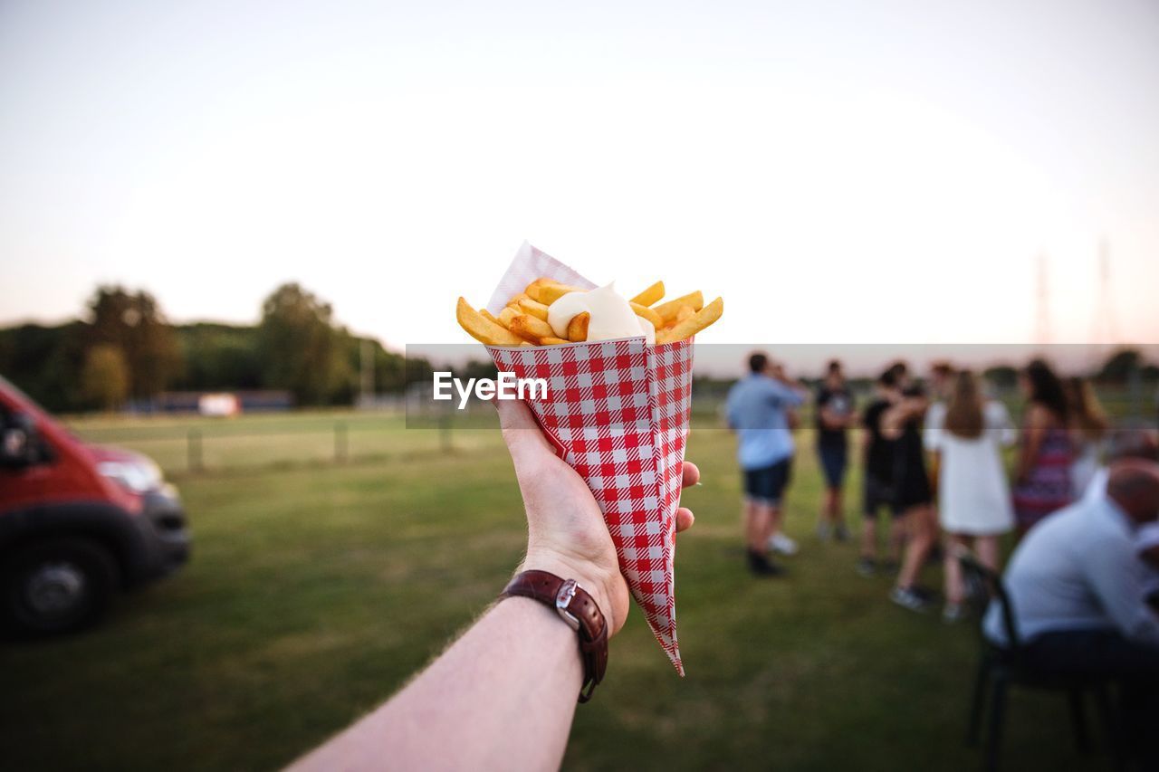 Close-up of french fries held by person in one hand 