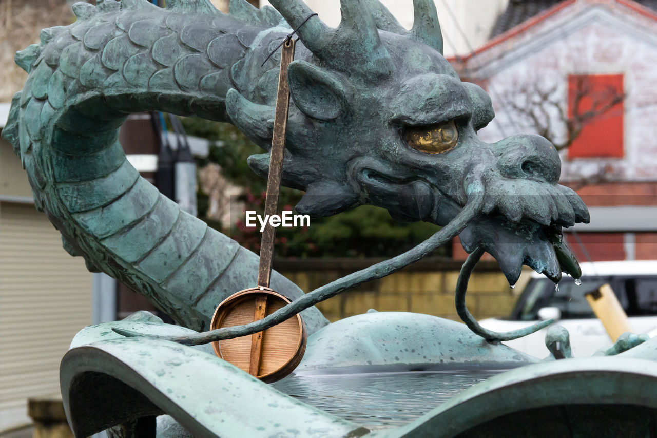 Basin with japanese dragon statue and wooden dipper for water purification