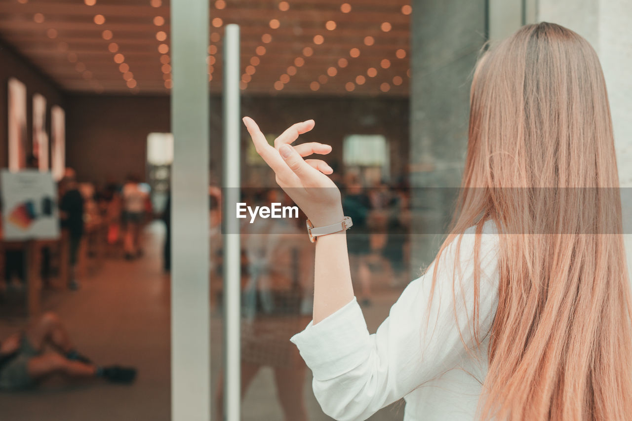 Rear view of woman gesturing while standing in restaurant