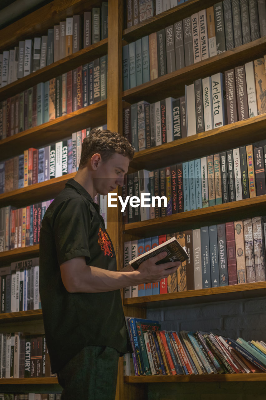 Young man reading book at library