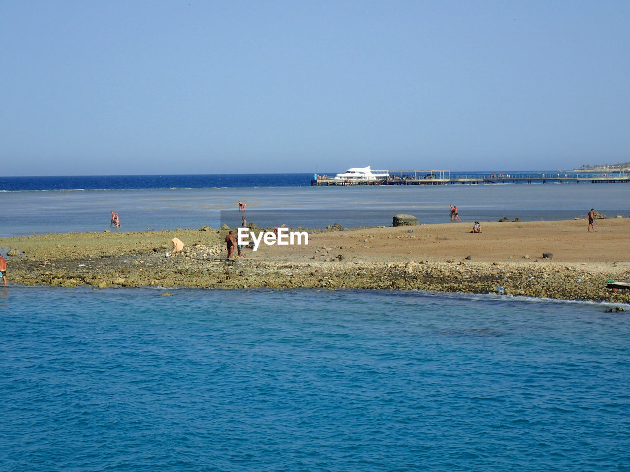 water, sea, body of water, land, sky, beach, shore, ocean, horizon, vacation, nature, scenics - nature, nautical vessel, blue, clear sky, beauty in nature, coast, group of people, holiday, travel, trip, horizon over water, transportation, day, bay, large group of people, travel destinations, tourism, wave, sunny, outdoors, crowd, tranquility, tranquil scene, tourist, mode of transportation, summer, idyllic, sunlight, leisure activity, coastline, copy space, lifestyles, men, ship, architecture, non-urban scene