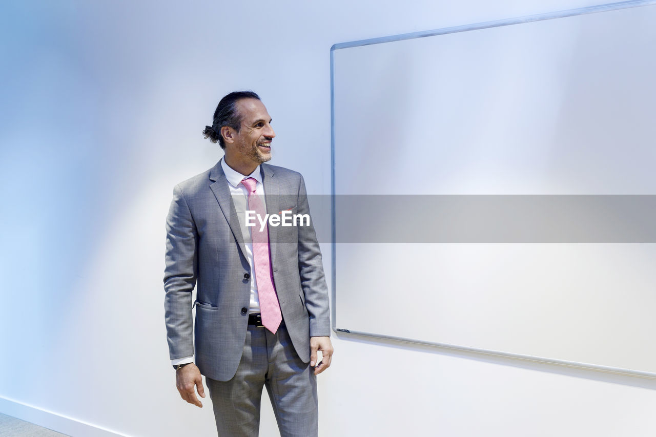 Happy businessman looking at whiteboard in conference room