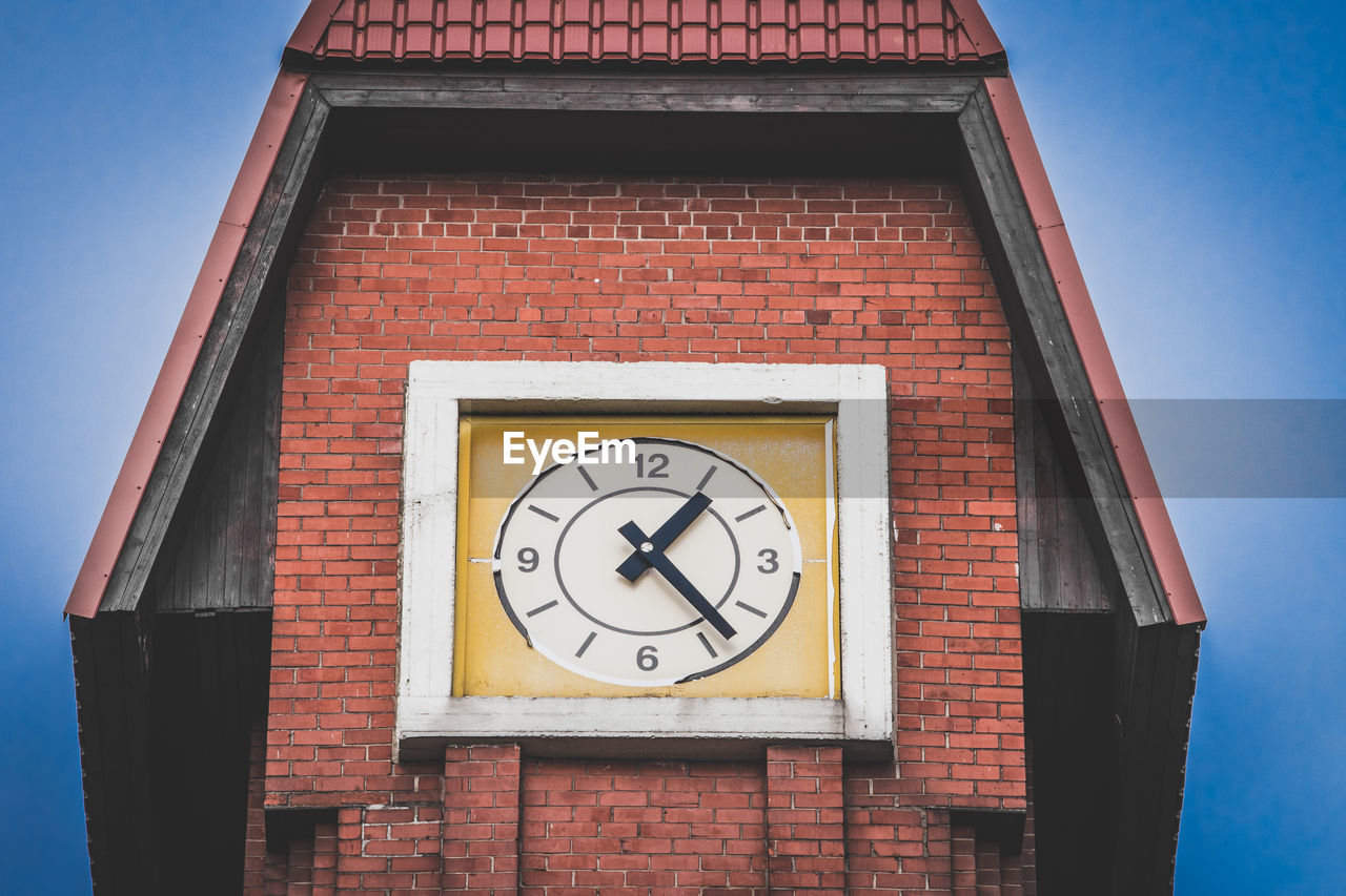 LOW ANGLE VIEW OF CLOCK ON BRICK WALL