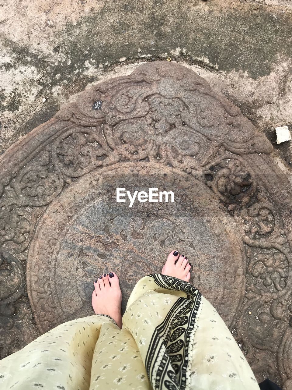 LOW SECTION OF WOMAN STANDING ON COBBLESTONE