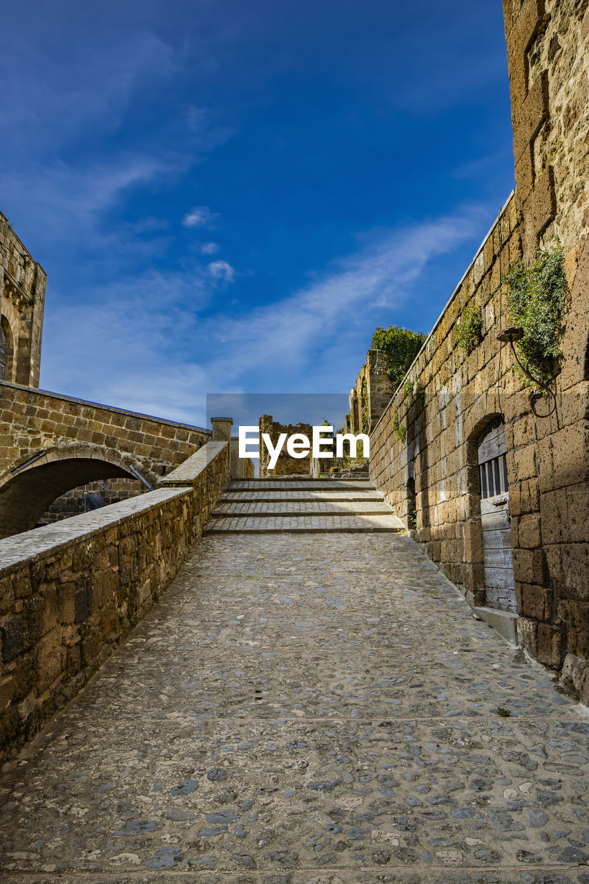 architecture, built structure, sky, wall, history, building exterior, the past, building, cloud, travel destinations, ancient history, nature, city, ruins, the way forward, no people, travel, wall - building feature, ancient, rock, old, fort, tourism, blue, street, outdoors, footpath, fortification, day, stone wall, stone material, road, medieval, castle, surrounding wall, staircase, fortified wall, cobblestone