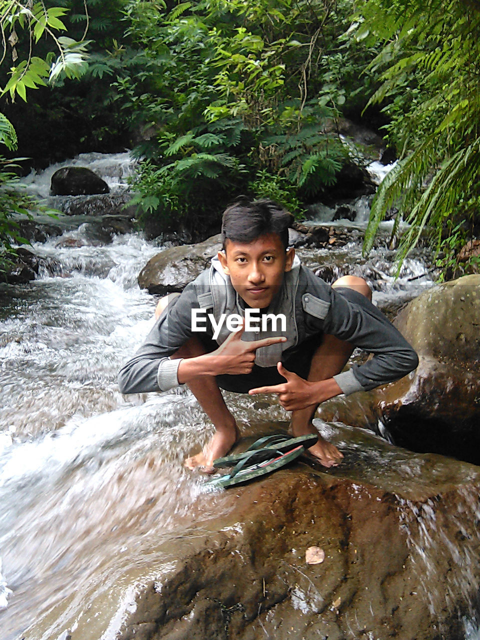 Pose portrait of young men sitting in river flow