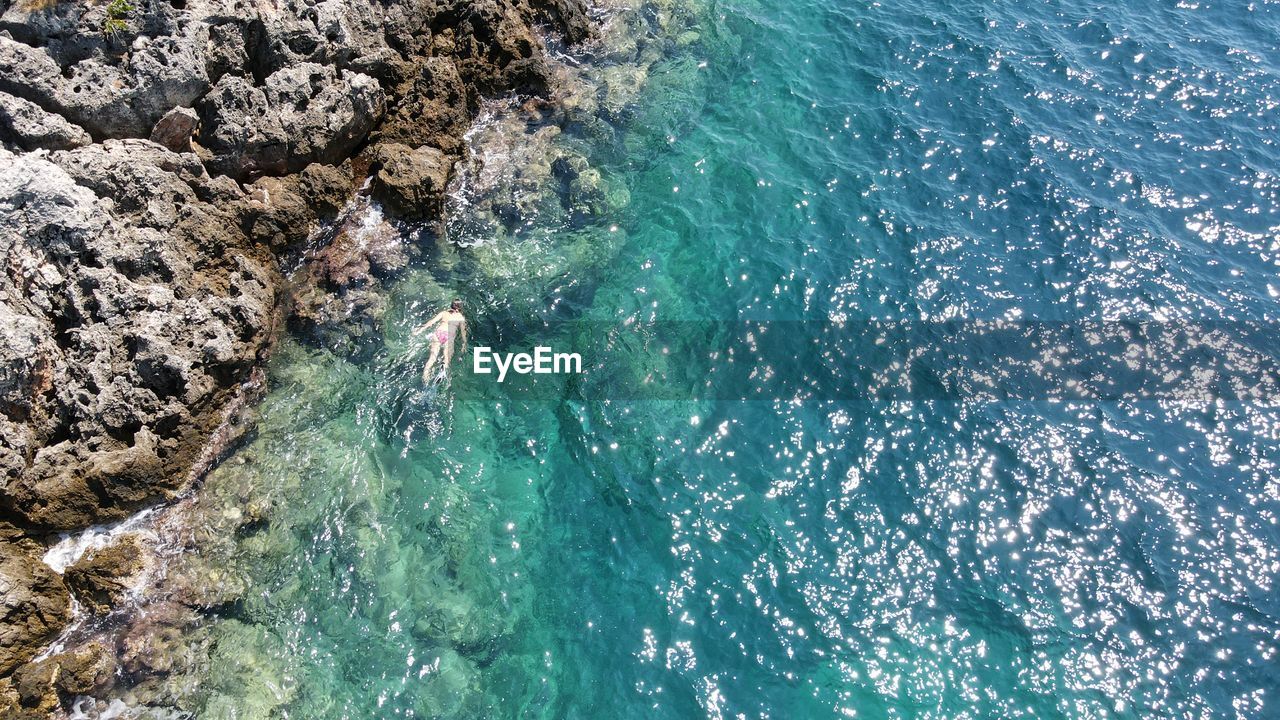 HIGH ANGLE VIEW OF SWIMMING IN SEA