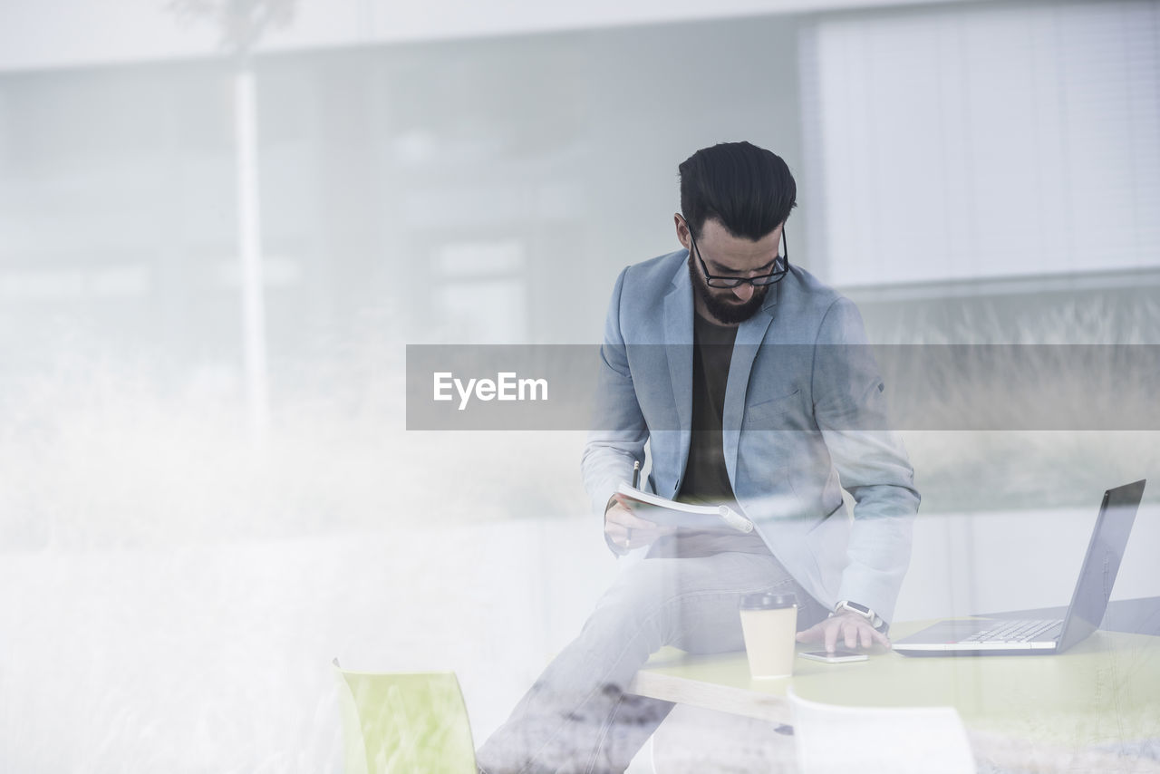 Young businessman sitting on desk, working