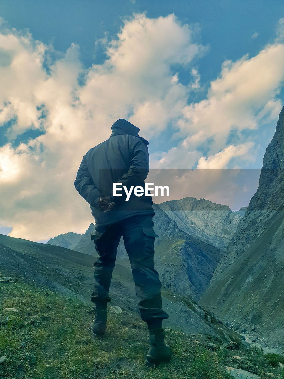 Rear view of man standing on mountain against sky