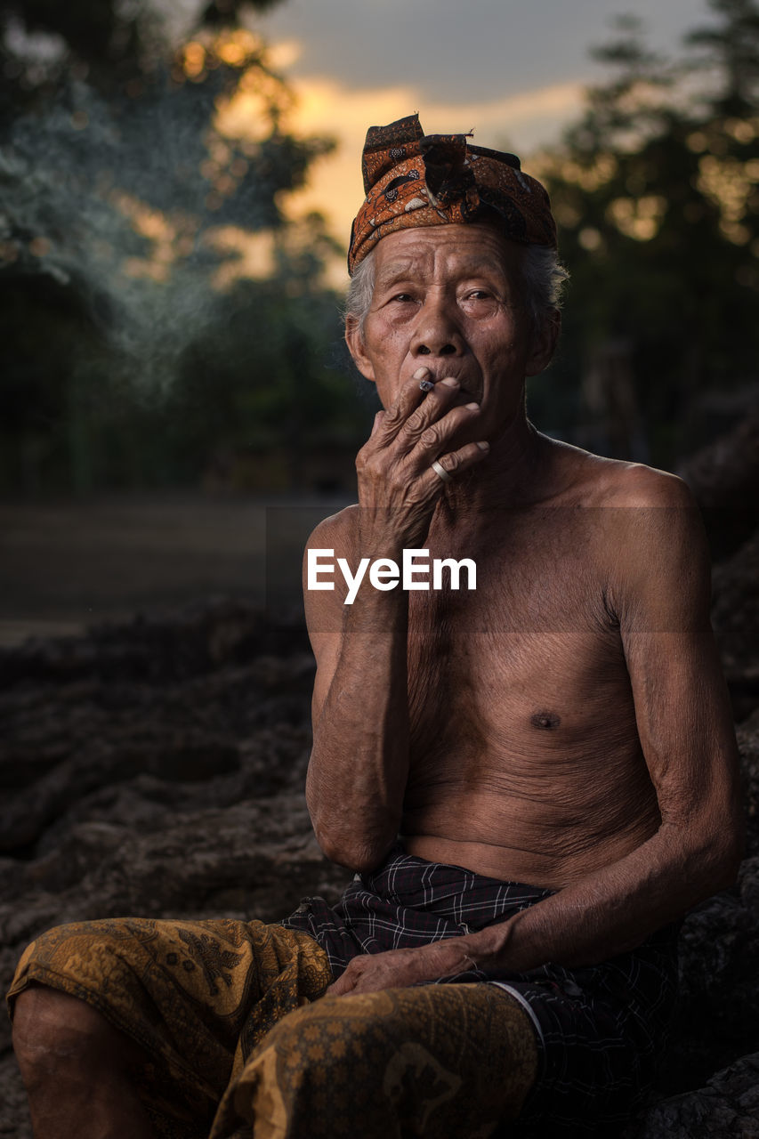 Old man smoking with sunset background