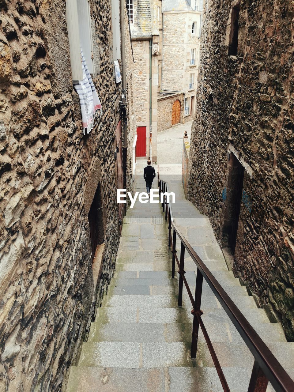 Rear view of man walking on staircase in building