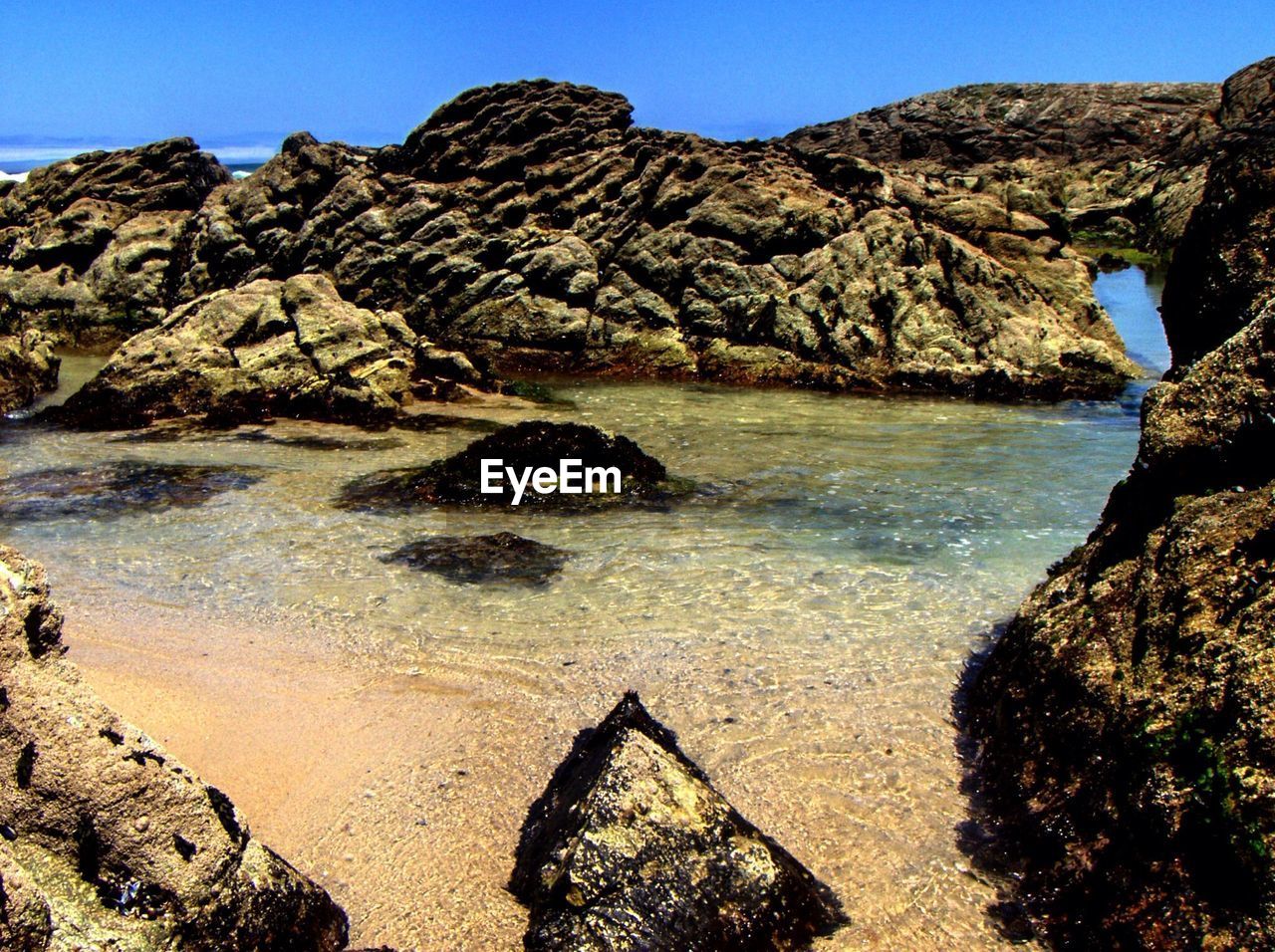 View of sea with rock formations against blue sky