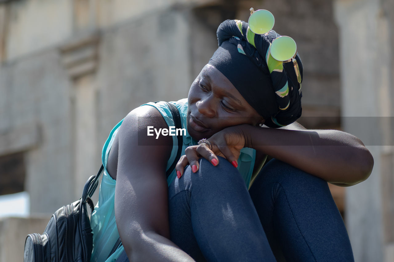 African woman with headdress and round sunglasses from ghana sitting and enjoying in takoradi ghana