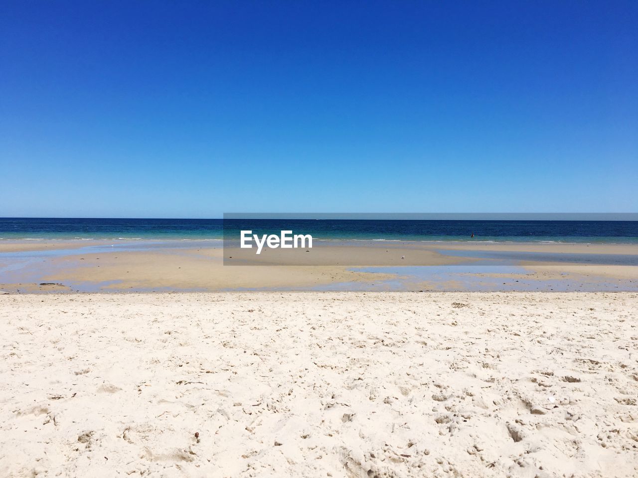 Scenic view of beach against clear blue sky