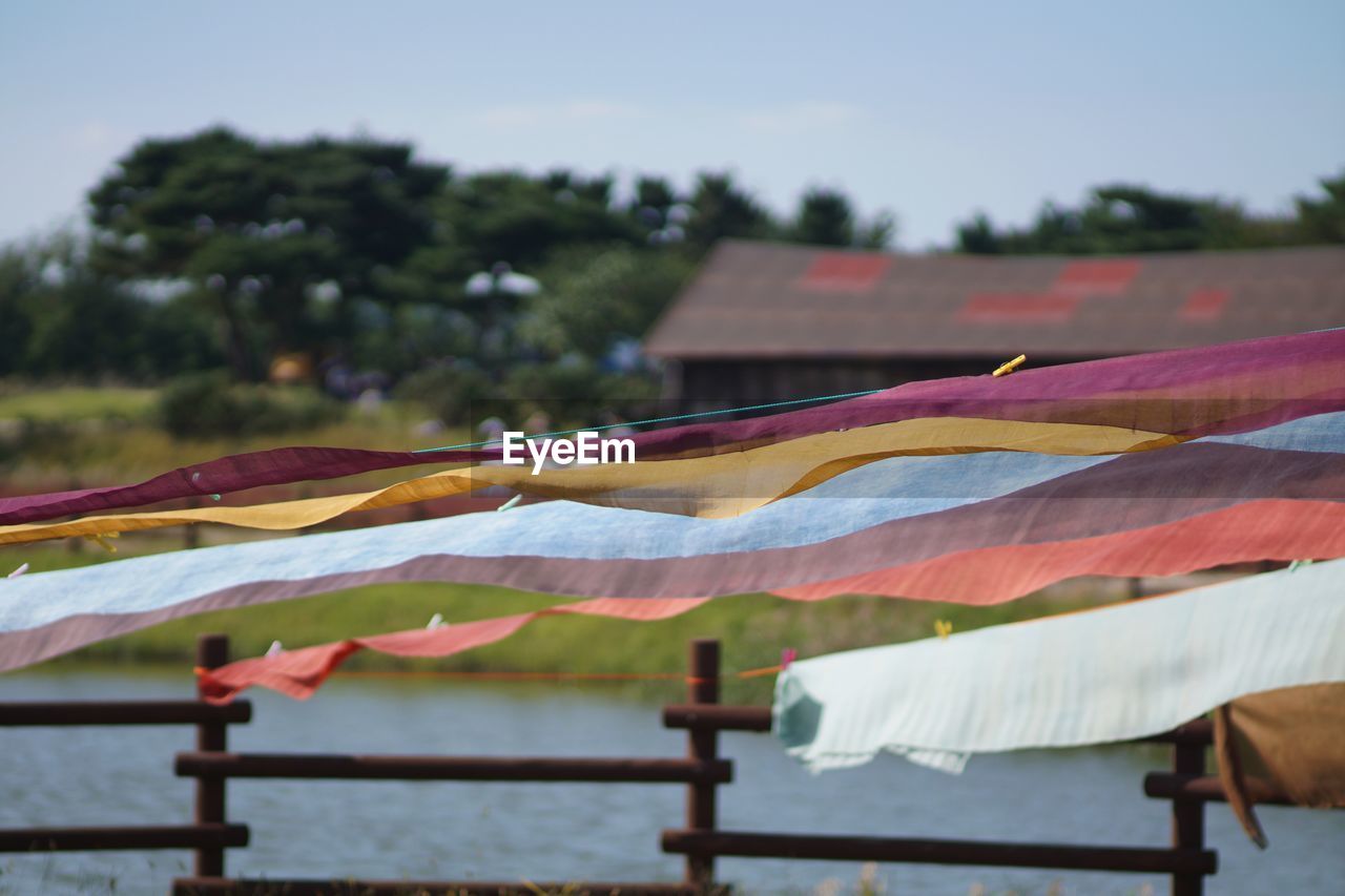 nature, sky, no people, multi colored, day, textile, focus on foreground, outdoors, drying, water, hanging, environment, plant, clothesline, architecture, tree, protection, laundry
