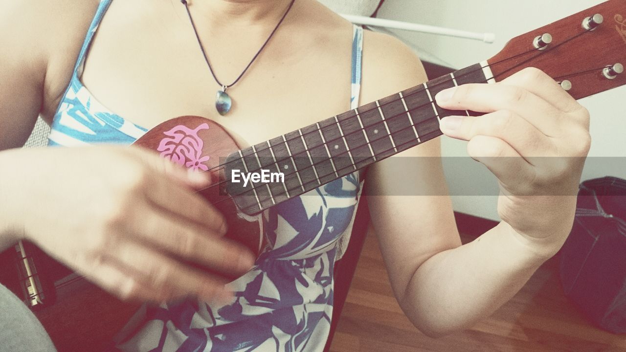 Midsection of woman playing ukulele