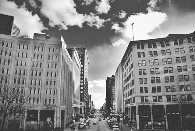 VIEW OF CITY STREET AND BUILDINGS AGAINST CLOUDY SKY