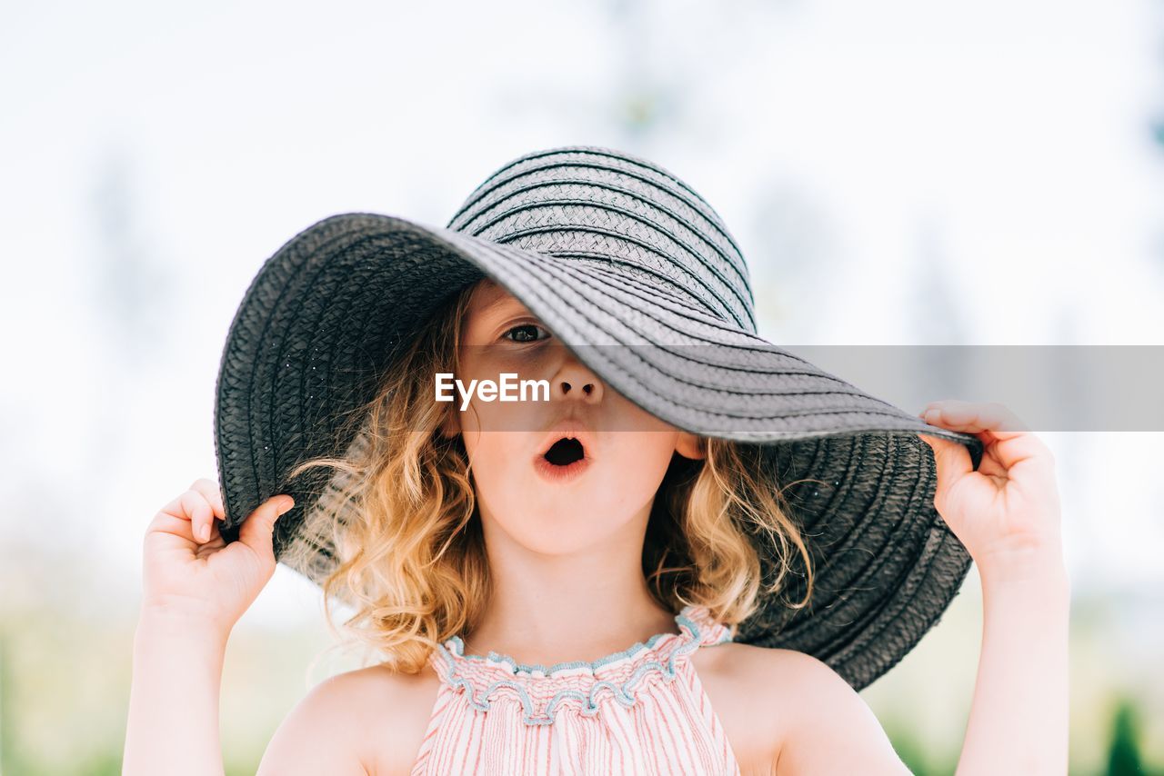 Portrait of a young girl pulling a funny expression with a sun hat on